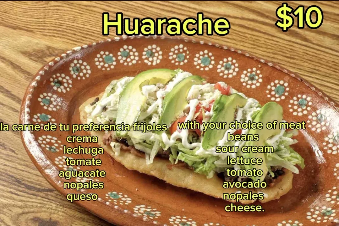 Huarache with beans, sour cream, lettuce, tomato, avocado, nopales, and cheese